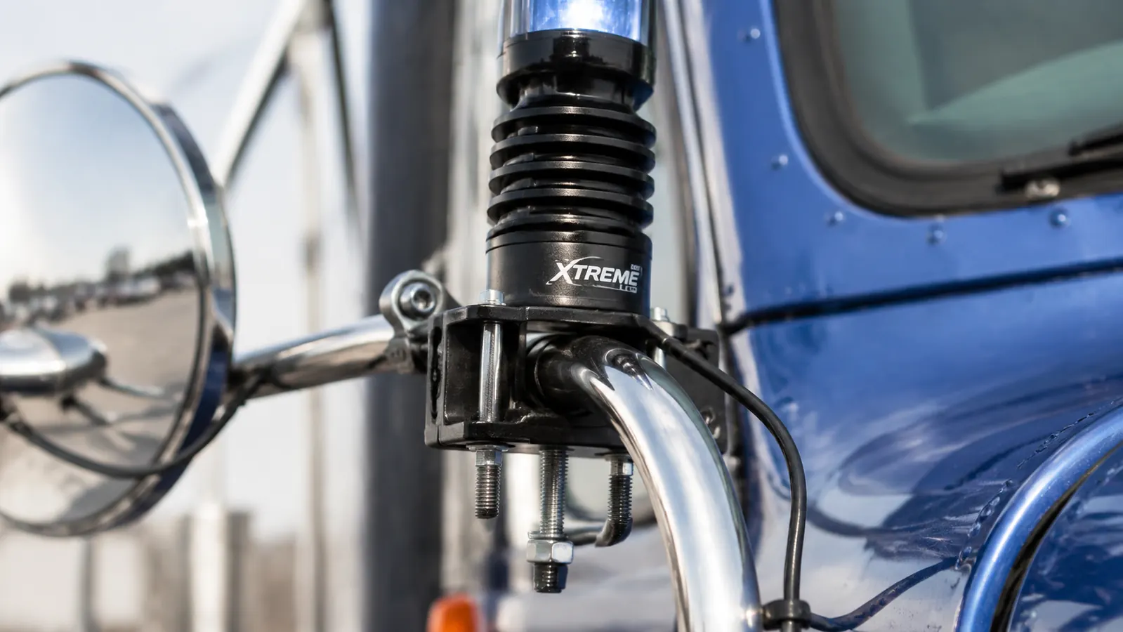 Close-up of an LED whip light base mount secured to a semi truck mirror bracket, waterproof connections visible