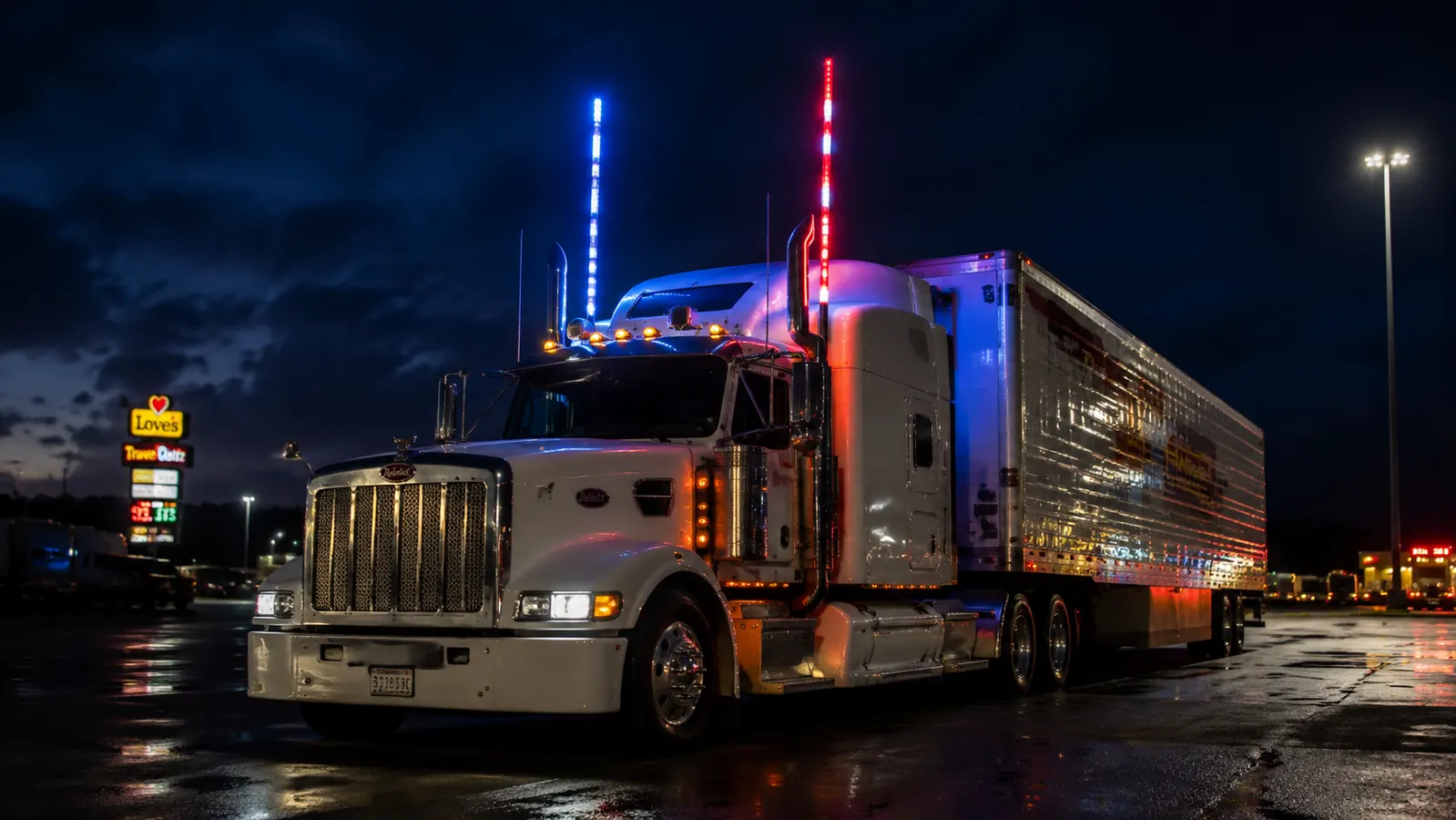 Two LED whip flag poles mounted on a semi truck cab at night, glowing red white and blue